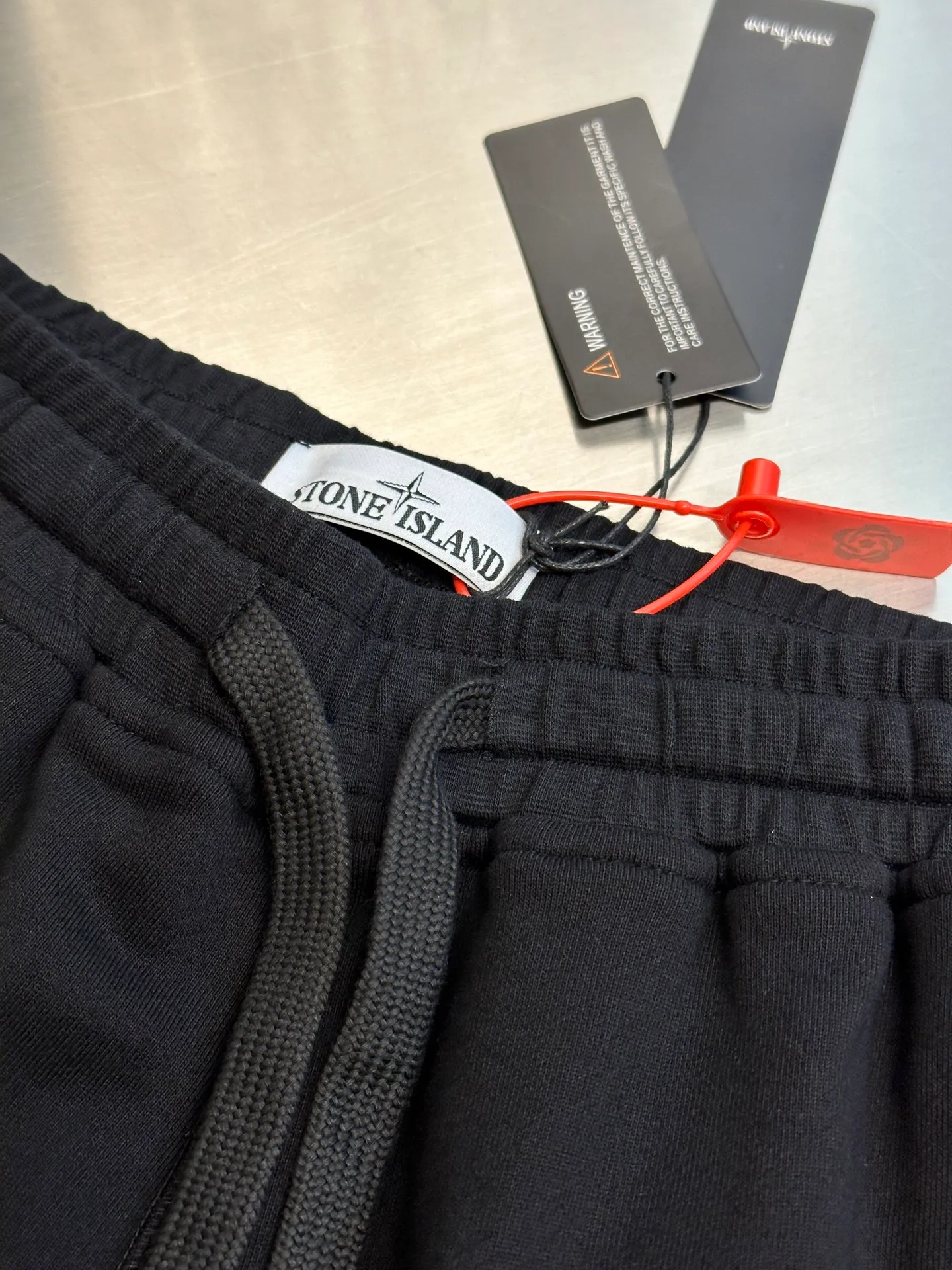 🅿️400 Stonelsland Stone Island Badge Embroidered Shorts Customized to the purest and most luxurious terry cloth, with iconic red Compass badge embroidery on the side of the pants and stitching art. The beauty of contrasting colors, red stitching jumps on the black base.  Using imported machine embroidery technology, advanced computer control systems and precision mechanical components, the red Compass badge embroidery operation is realized.  Special machine for reverse topstitching and fine sewing process. Special machine is used for topstitch sewing. It requires careful preparation of the reverse side of the garment before sewing to ensure that the sewing lines are straight, the stitches are even, and the edges are smooth and beautiful.  size：s m l xl